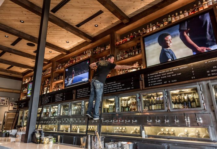 Union Bear Brewing Co. bar server on a ladder grabbing bottles off the wall