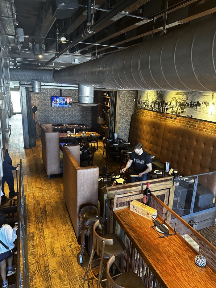 A restaurant interior with wooden floors, brown leather booths, and industrial-style exposed ducts captures the Urban Crust vibe.