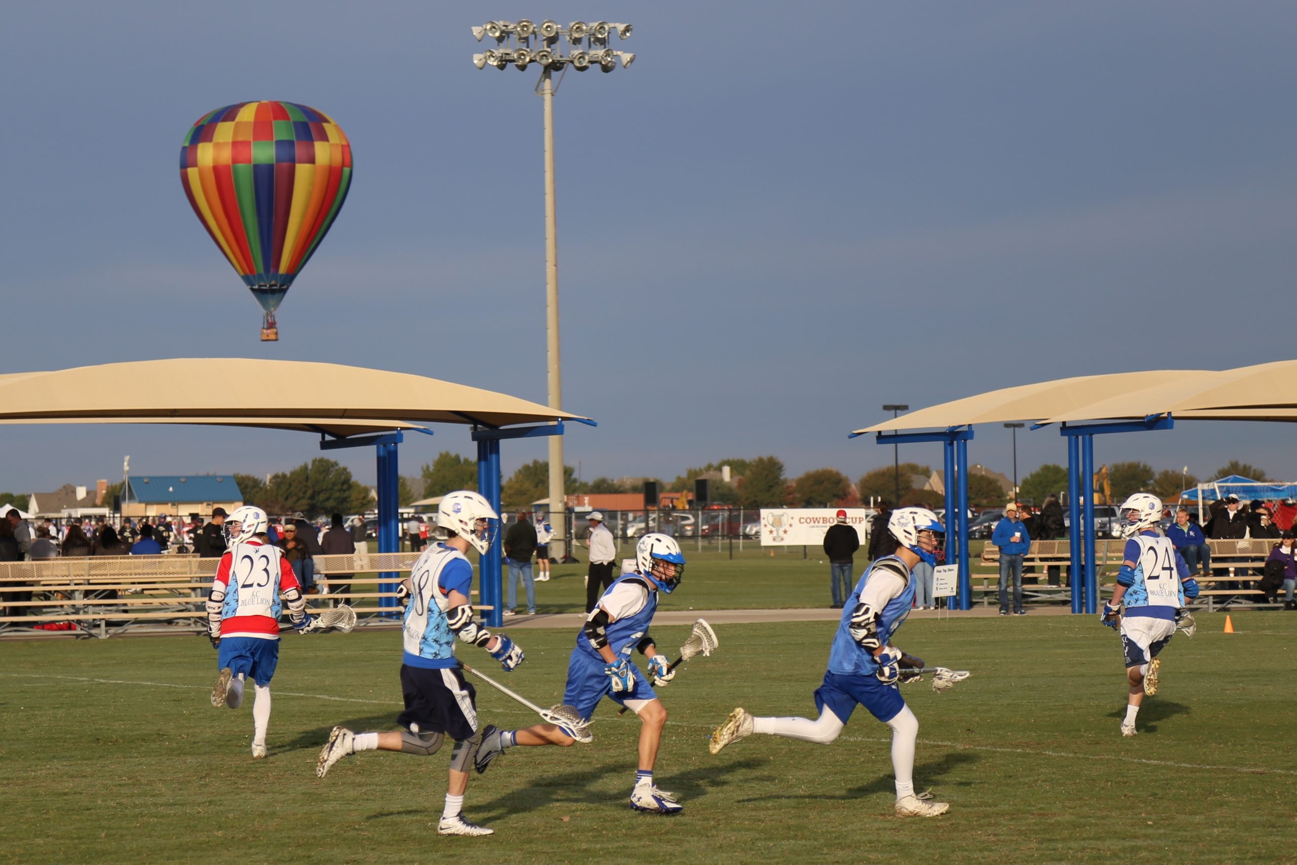 Lacrosse at Russell Creek Park in Plano with players and a hote air balloon in the air