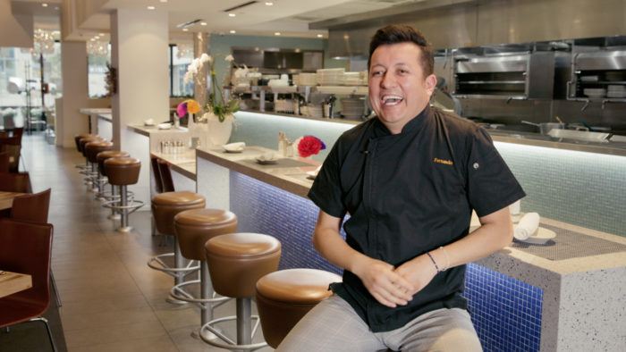 Fernando sits on a stool in front of the bar and spreads joy about how much his customers love Mesero