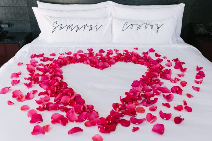 Renaissance pink rose petals in heart shape on bed