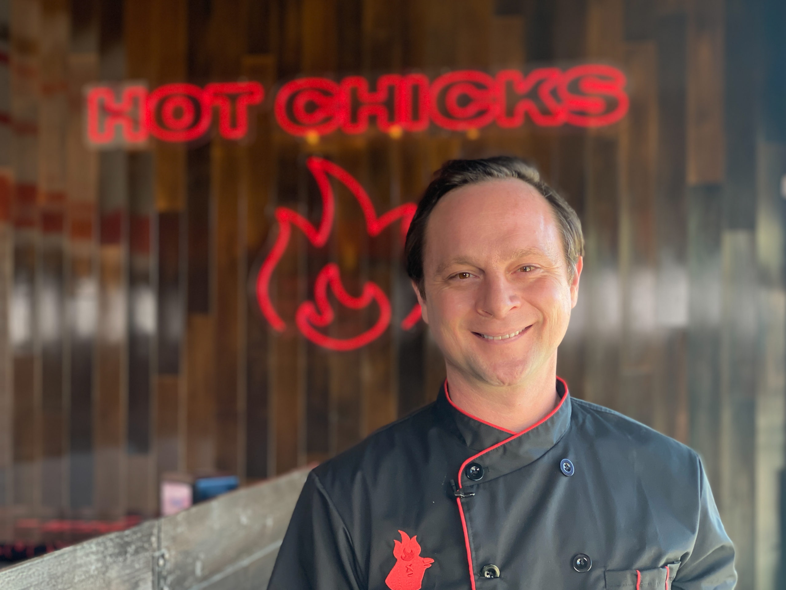 Hot Chicks owner with sign in background