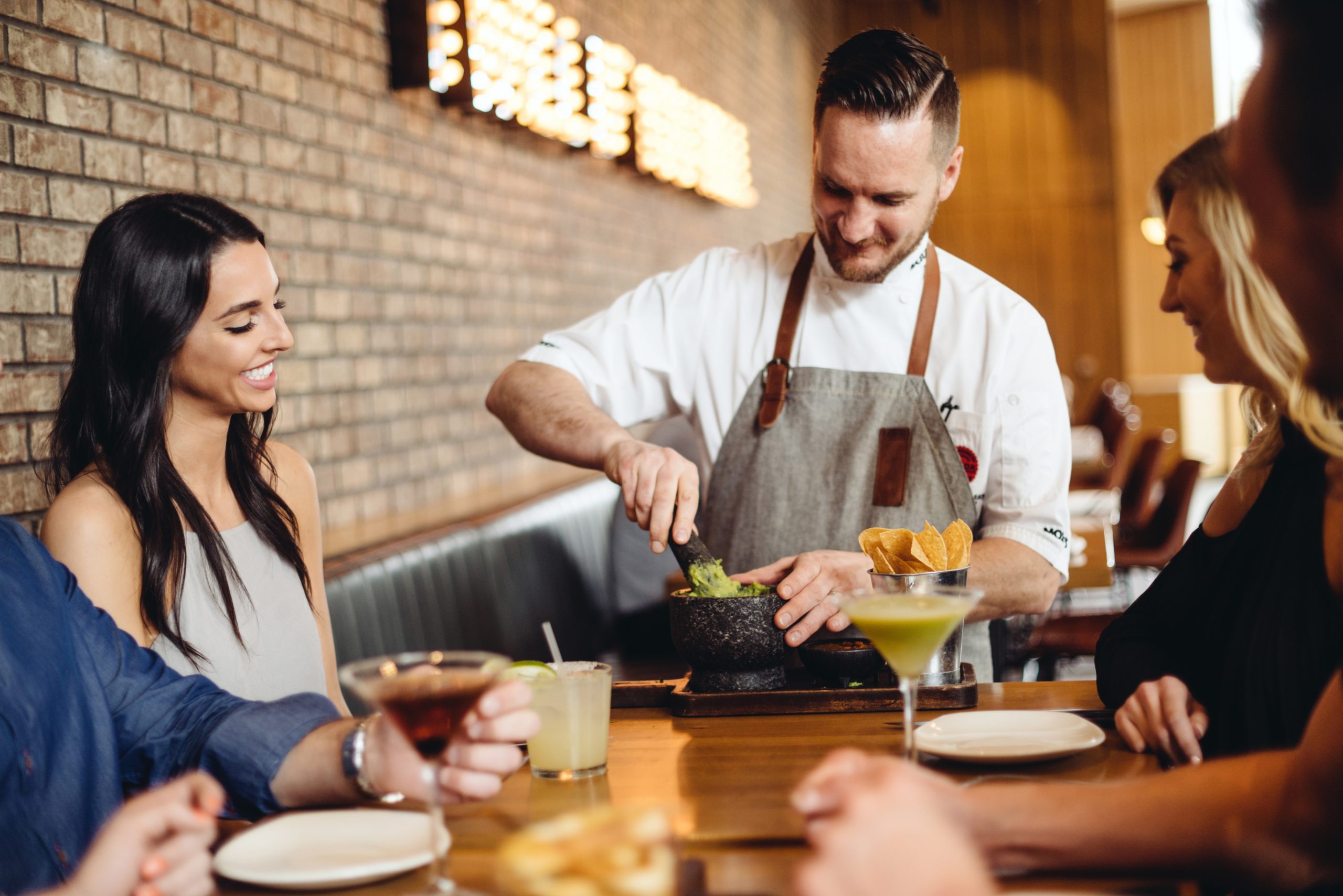 Moxie's guests enjoying DFW Restaurant Week with drinks and table-side guacamole