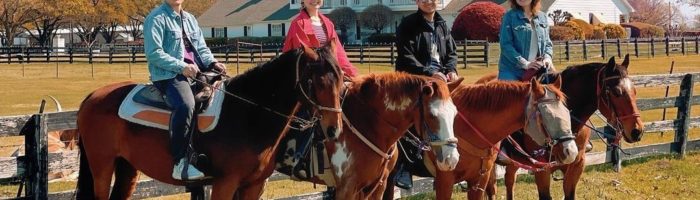 Riders on horseback in front of mansion