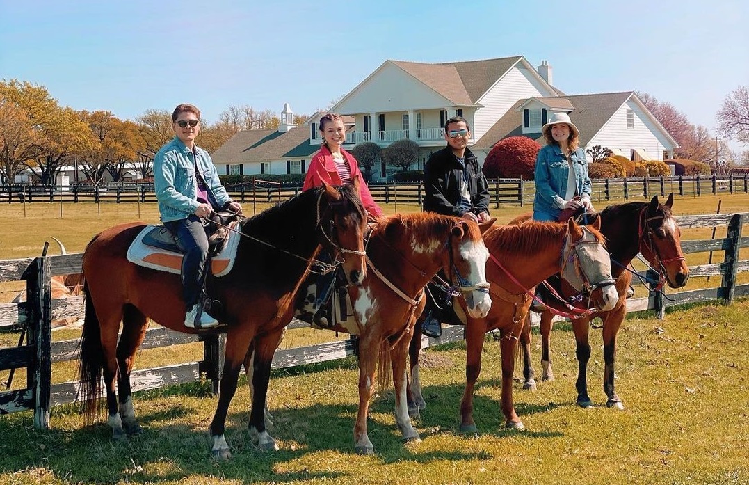 Riders on horseback in front of mansion