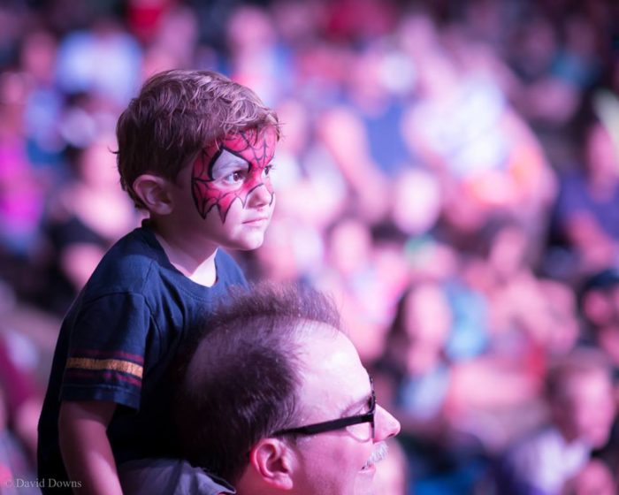 Kid on dad's shoulders with Spiderman face paint