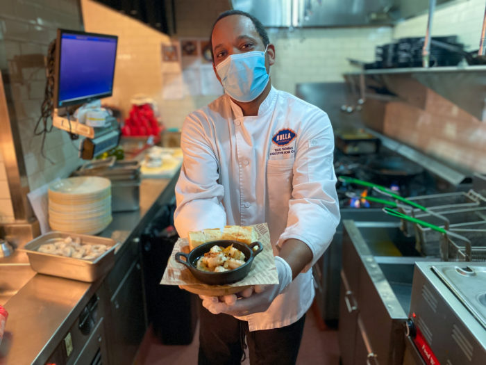 Bulla Gastrobar chef holding shrimp dish in kitchen