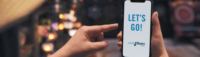 Let's Go and Visit Plano logoon mobile phone with girl pointing to phone