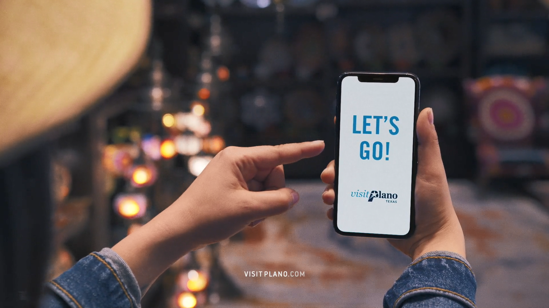 Let's Go and Visit Plano logoon mobile phone with girl pointing to phone