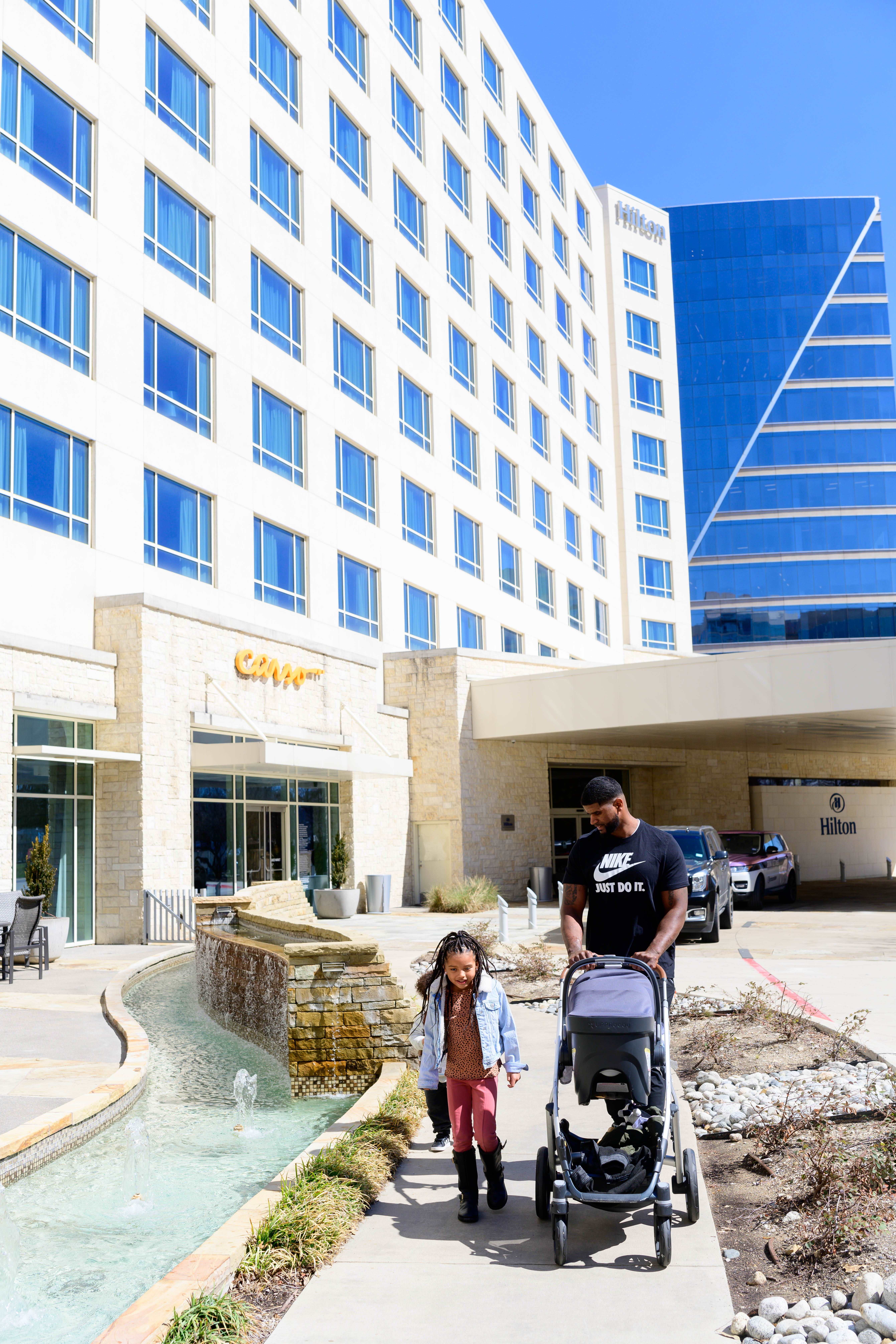 Daughter, dad, and baby strolling outside of the Hilton Granite Park