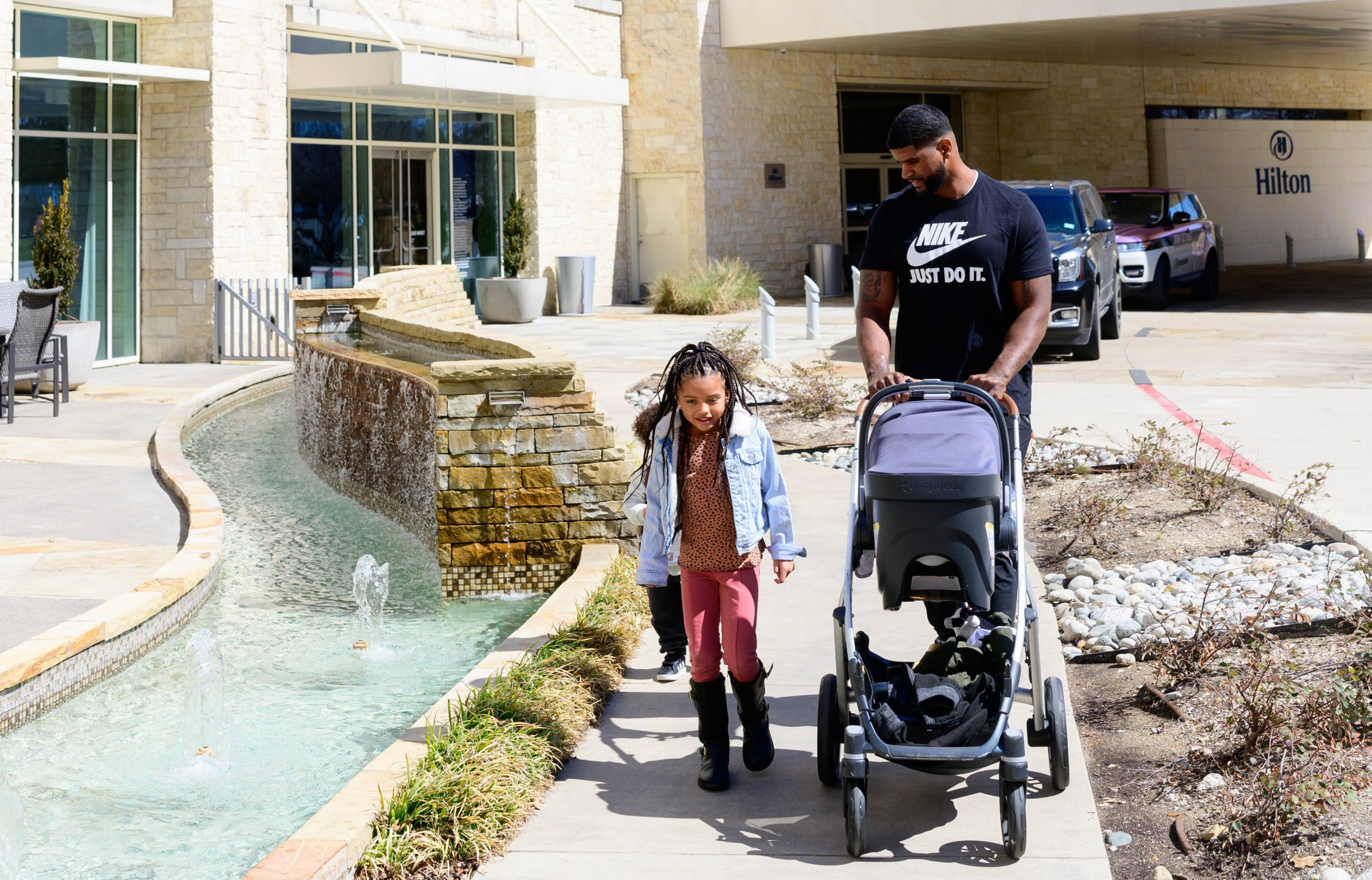 Girl, dad, and baby strolling outside of the Hilton Granite Park in Plano, TX