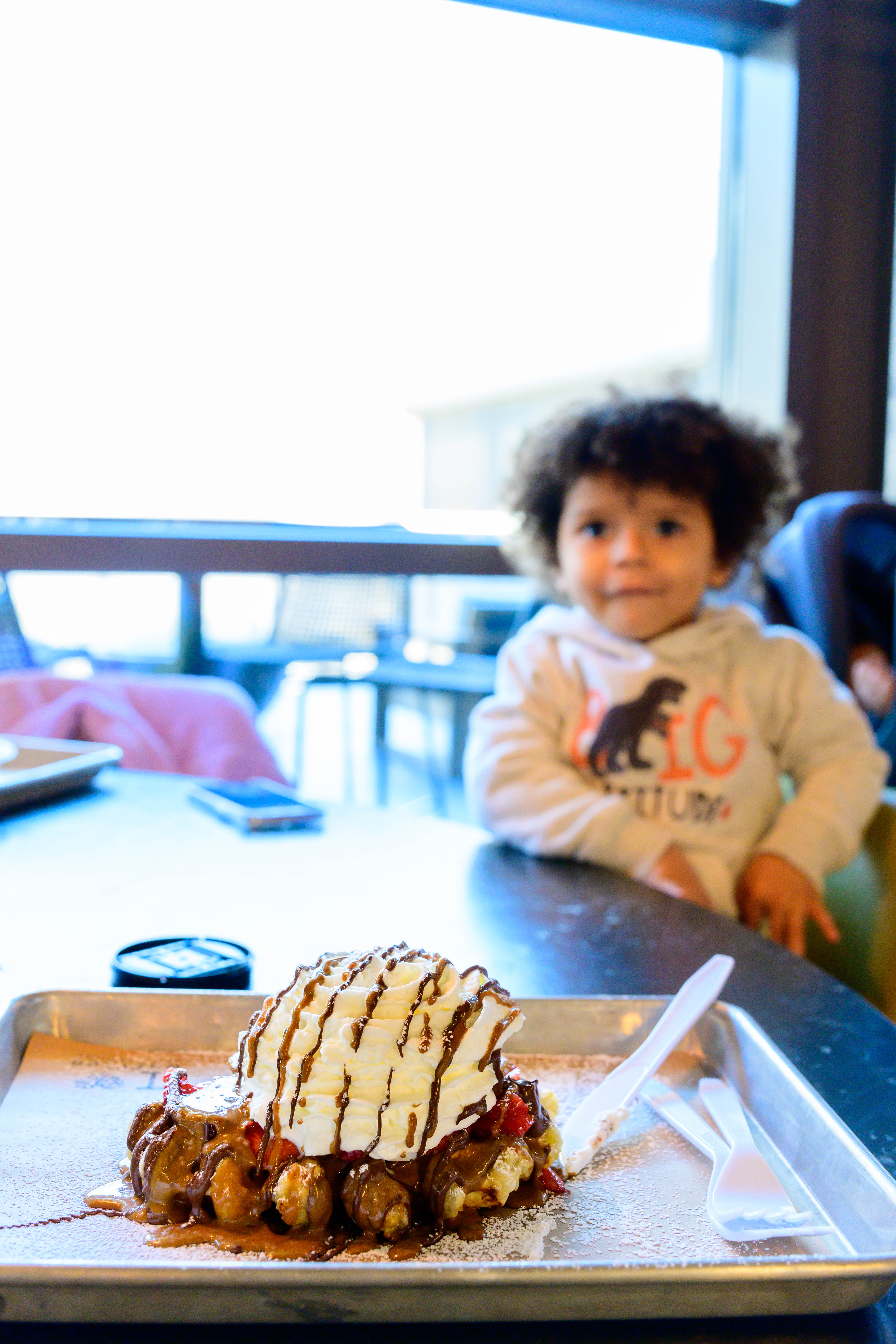 Boy toddler staring intently at waffle from Legacy Hall