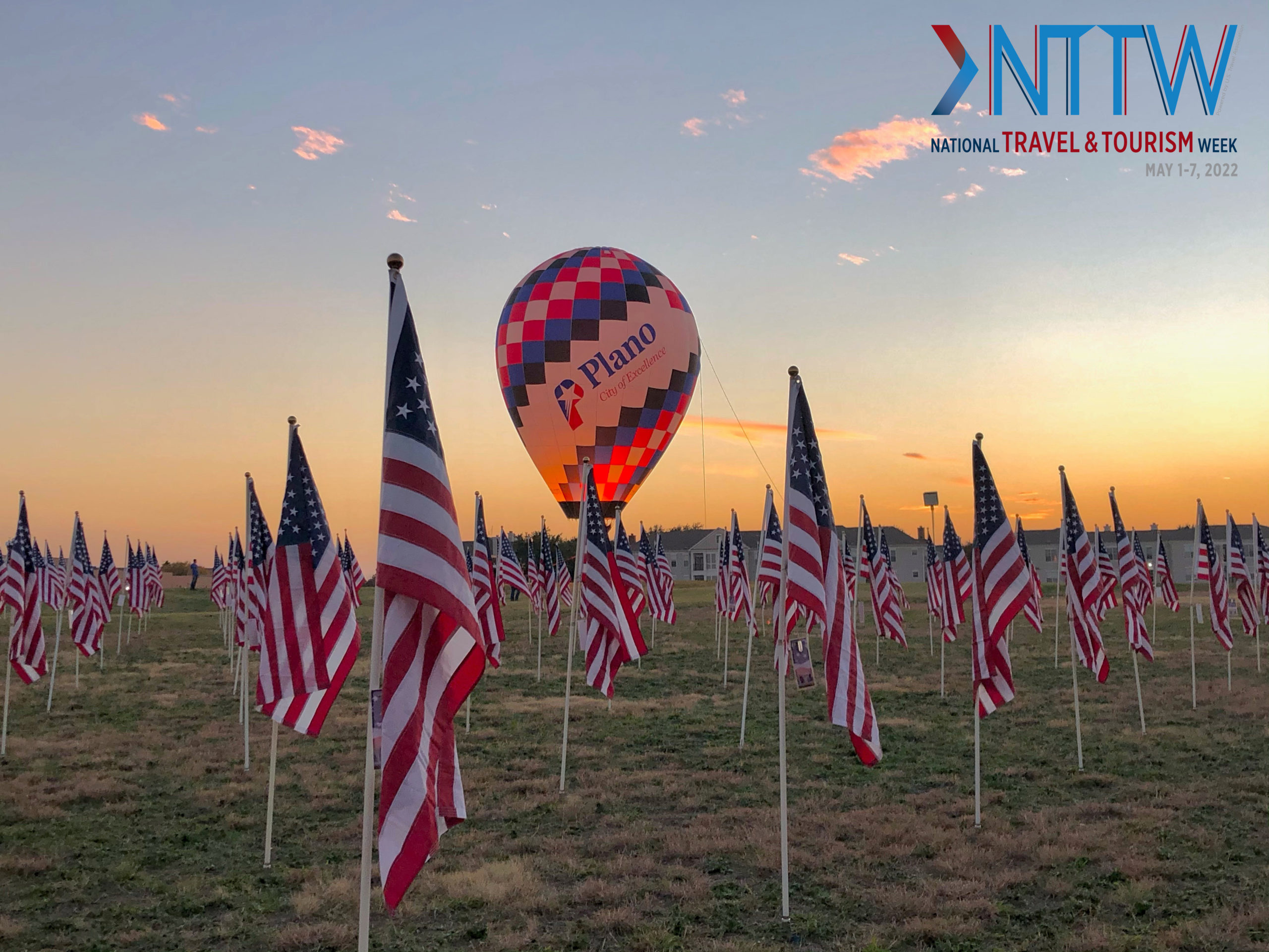 Plano hot air balloon in the field of American flags with the National Travel & Tourism Week logo
