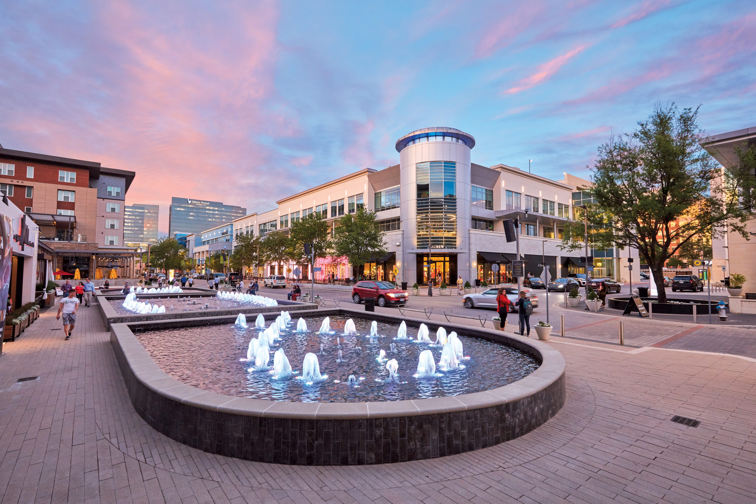 Legacy West fountains and people walking at dusk