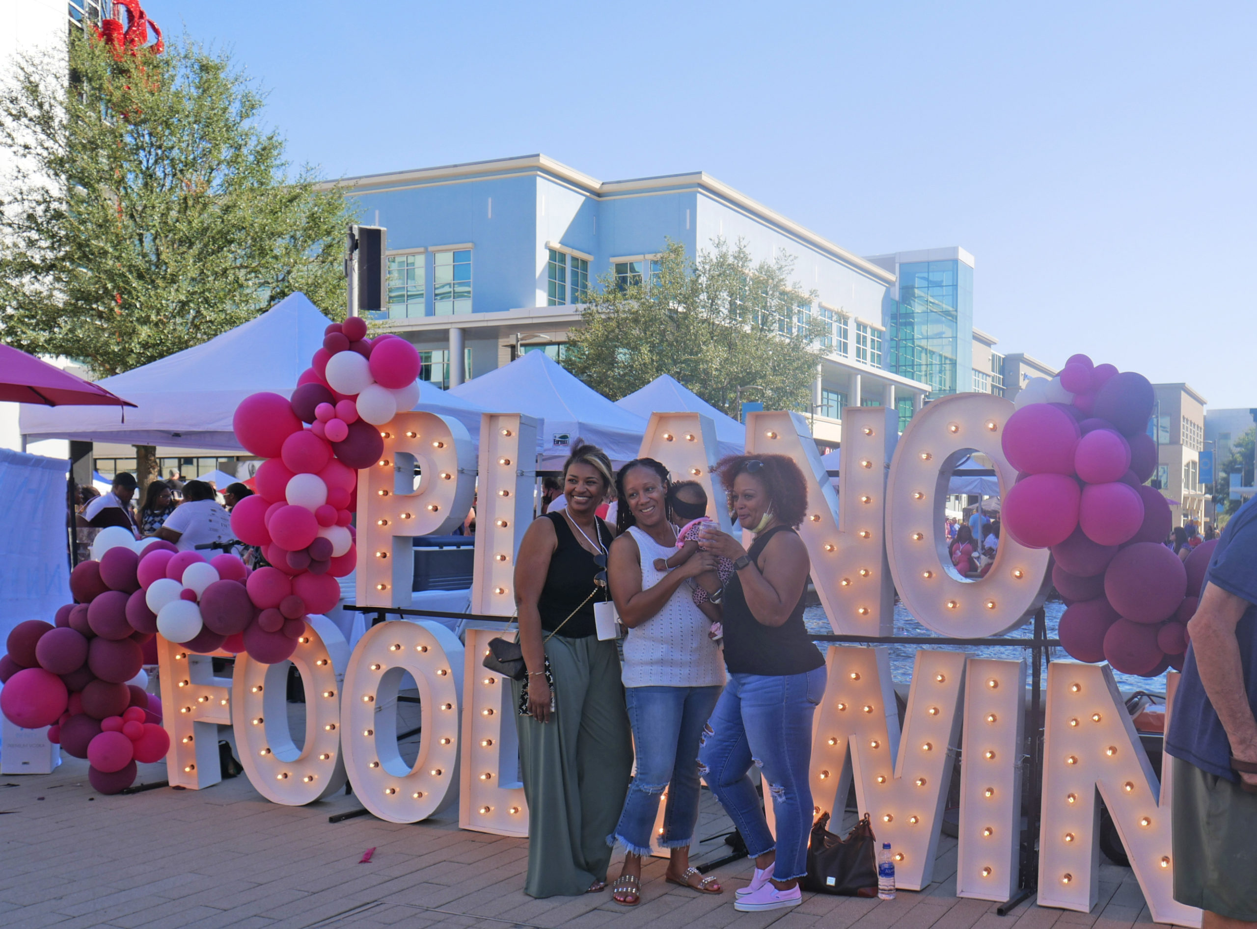 Attendees pose in front of Plano Food & Wine Festival giant letter backdrop during the fall season