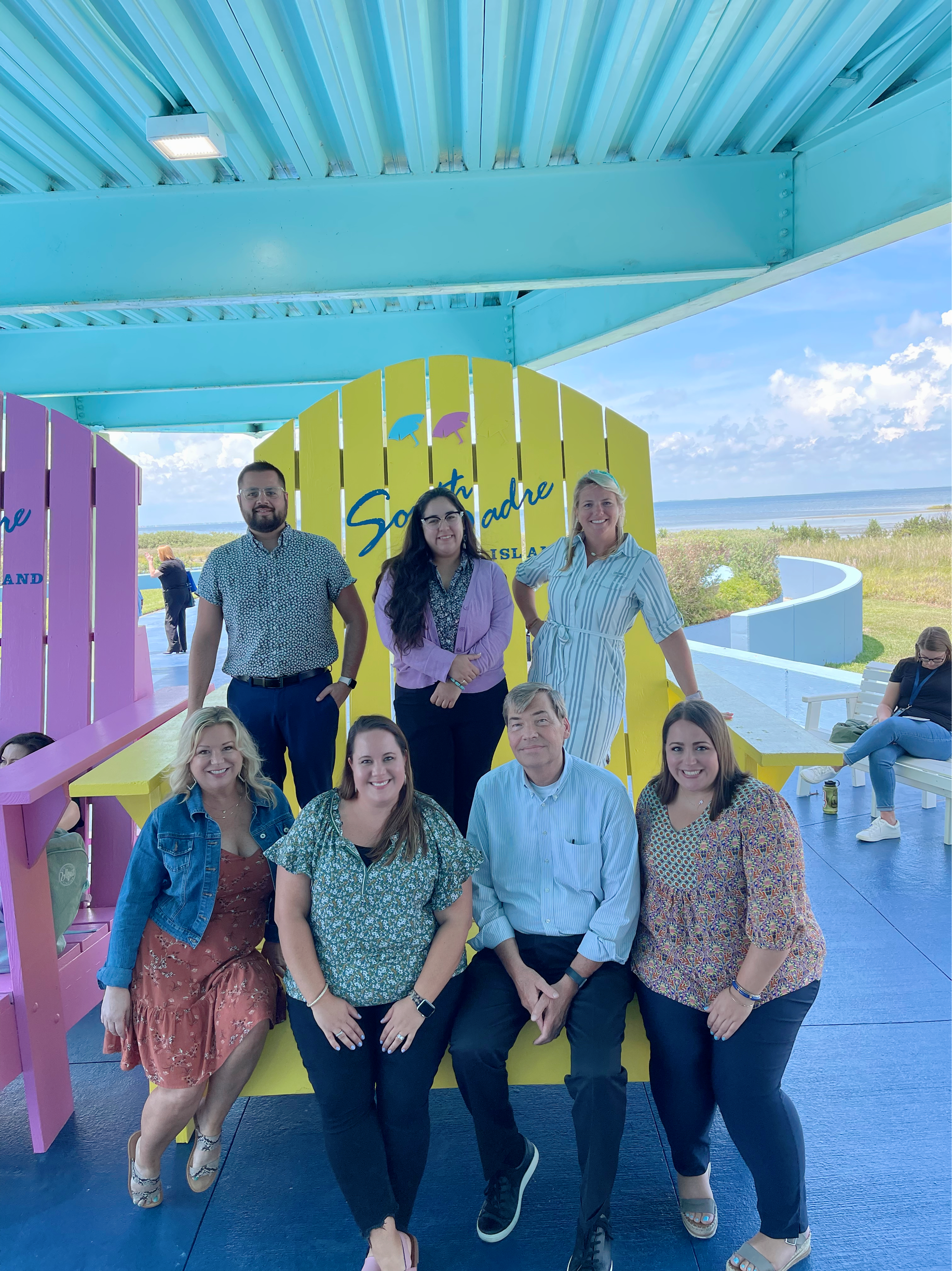 Visit Plano staff posing on massive South Padre Island beach chairs at TACVB conference