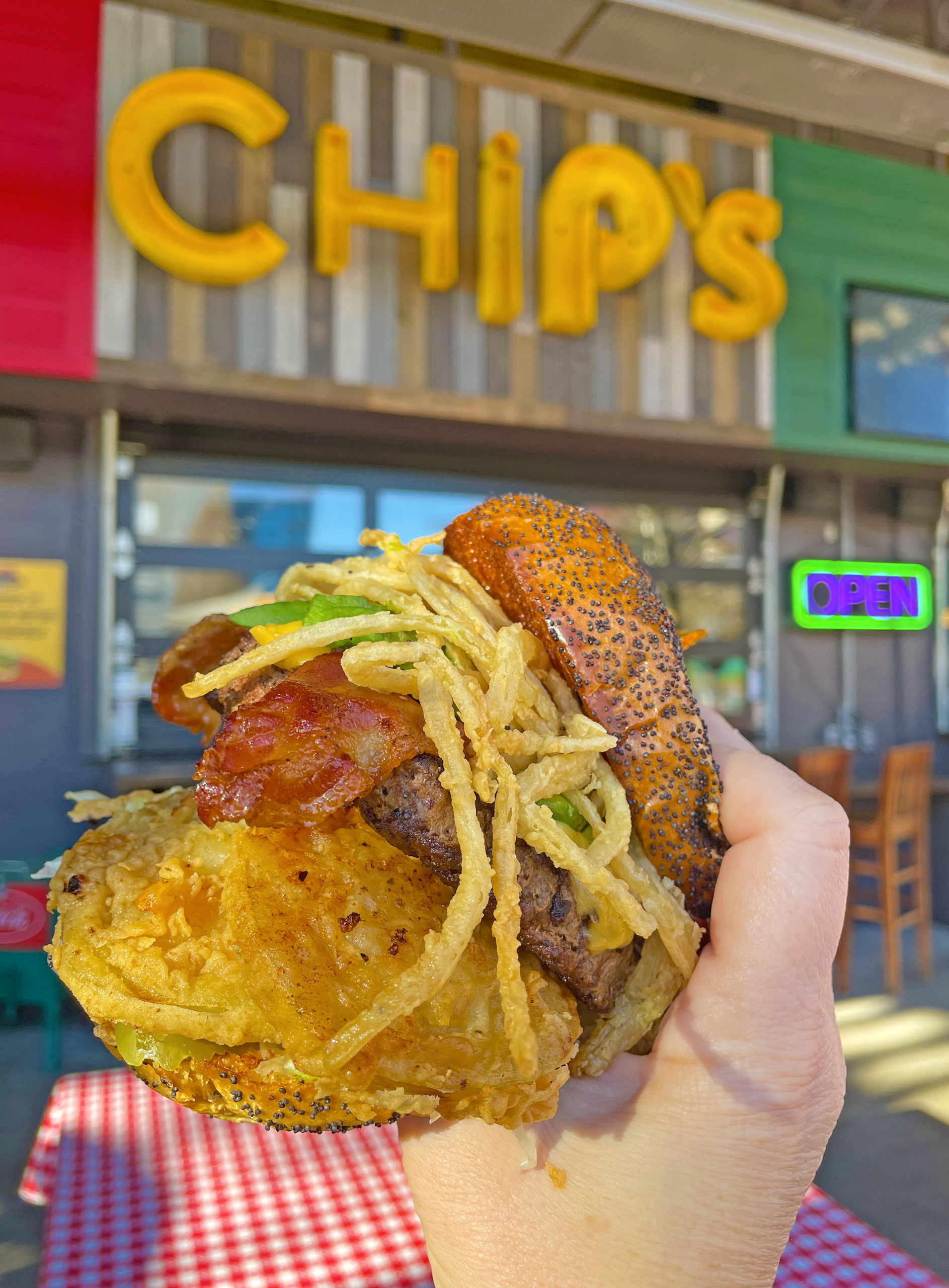 Chip's hamburger in hand with sign in the background