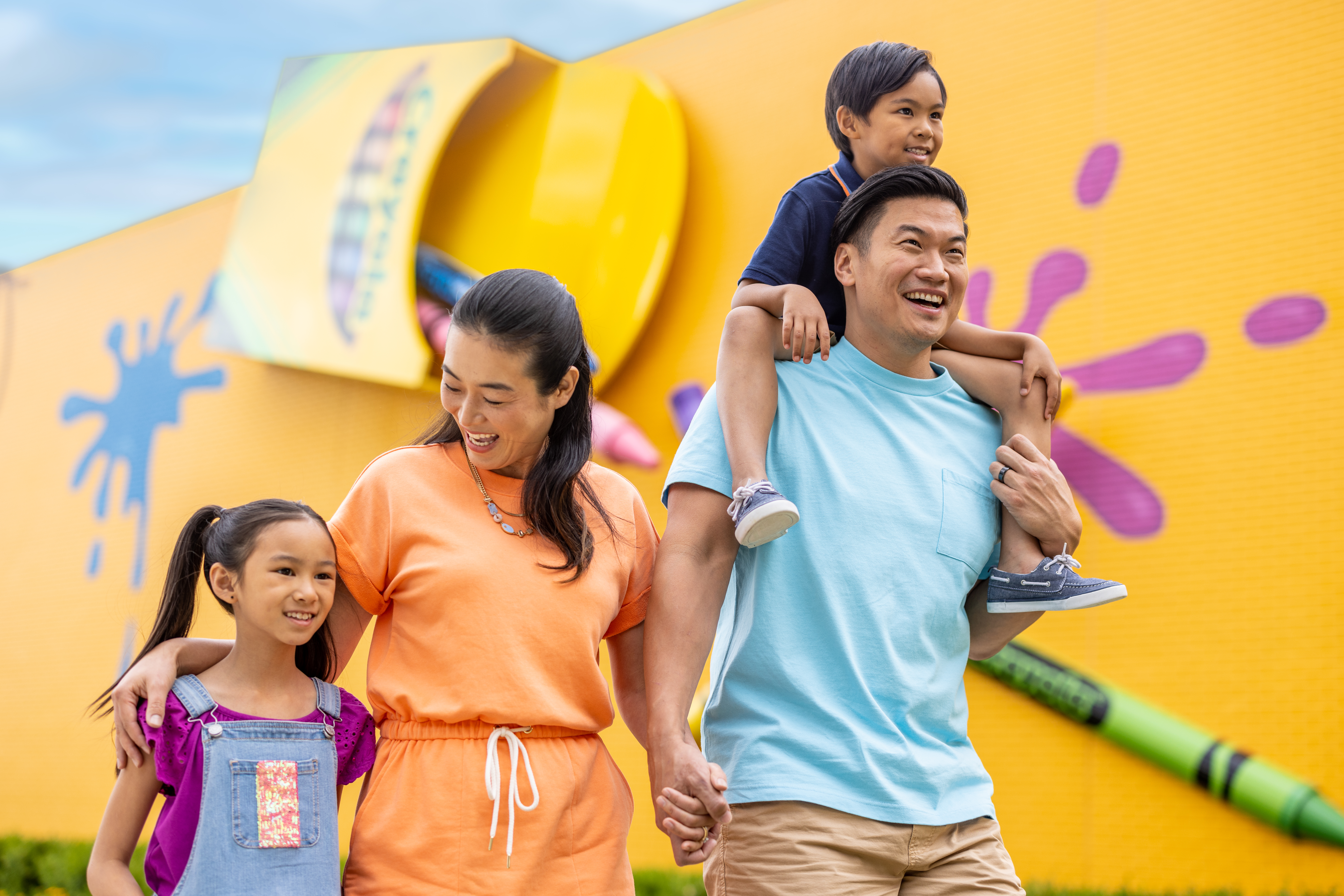 Family walking outside of Crayola Experience with yellow painted wall in background