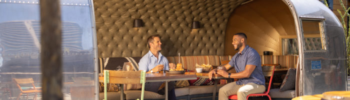 Two men dining inside of the open-air Airstream at Haywire restaurant in the Legacy District