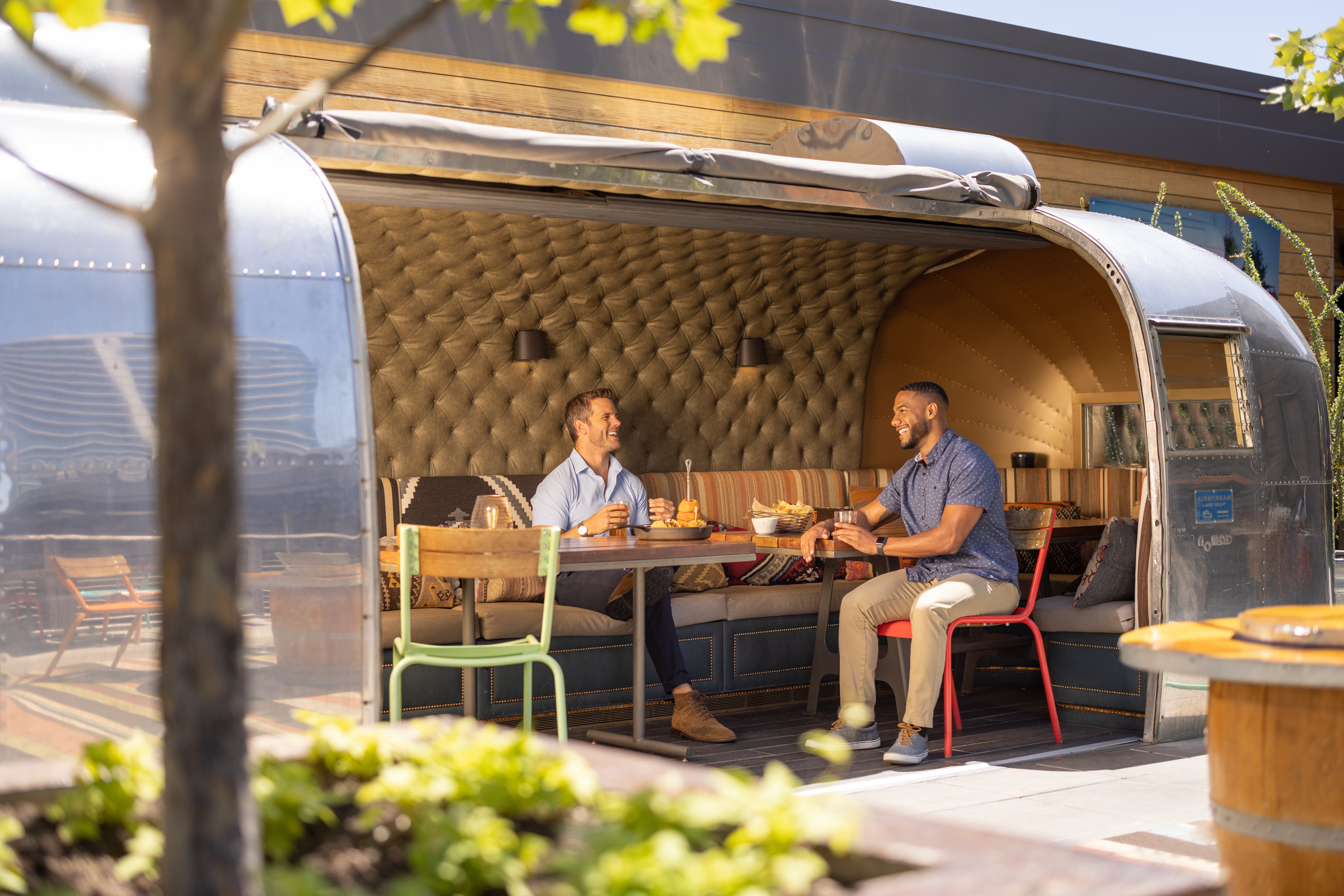 Two men dining inside of the open-air Airstream at Haywire restaurant in the Legacy District