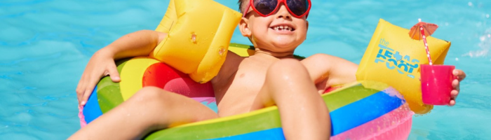 Summer Hotel Deals wording over a boy in the floatie in a pool with yellow arm floaties and a pink cup with an umbrella.