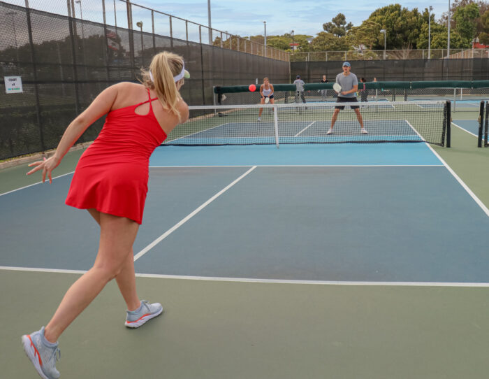 Women in red athletic dress playing pickleball