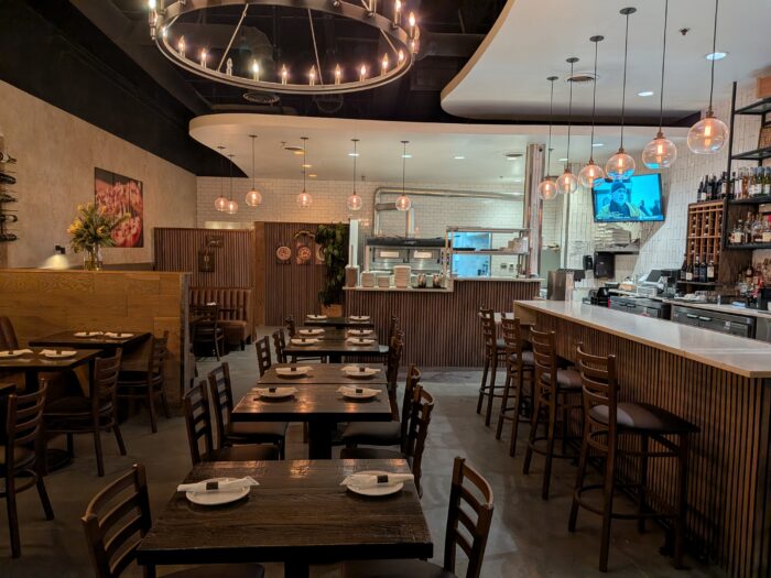 A warmly lit, modern restaurant with wooden tables and chairs at Unici Trattoria.