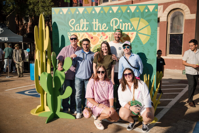 Group posing in front of a salt the rim sign
