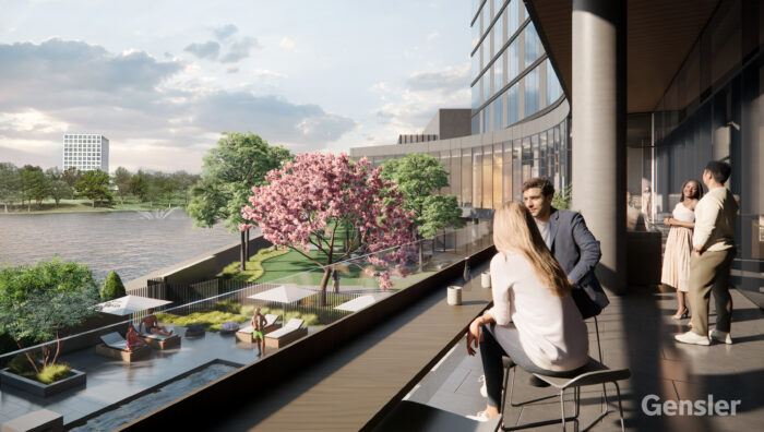 People converse on a balcony overlooking a river and landscaped garden with lounge chairs and a blooming pink tree, next to a modern glass building under a partly cloudy sky.