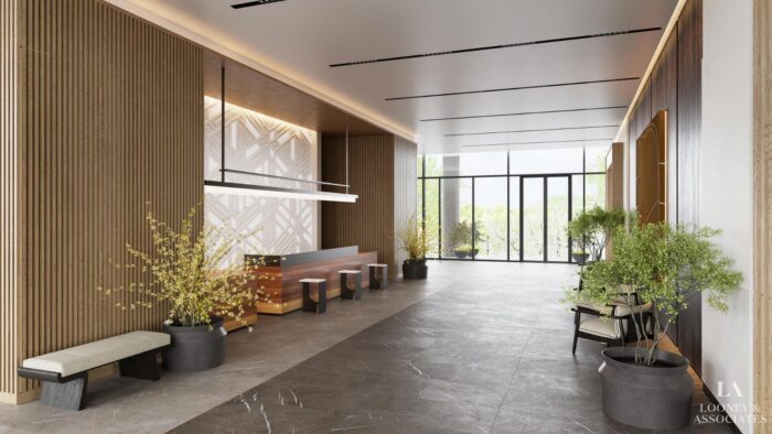 Modern lobby with minimalist décor, featuring wooden accents, benches, potted plants, a long counter, and large windows letting in natural light. The space has a clean and inviting atmosphere.