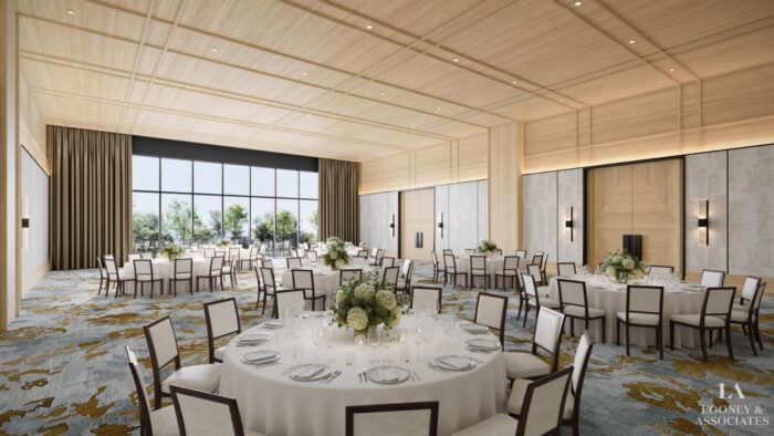 A spacious, elegant banquet hall with round tables set for an event, white tablecloths, floral centerpieces, wooden chairs, large windows bringing in natural light, and modern décor.